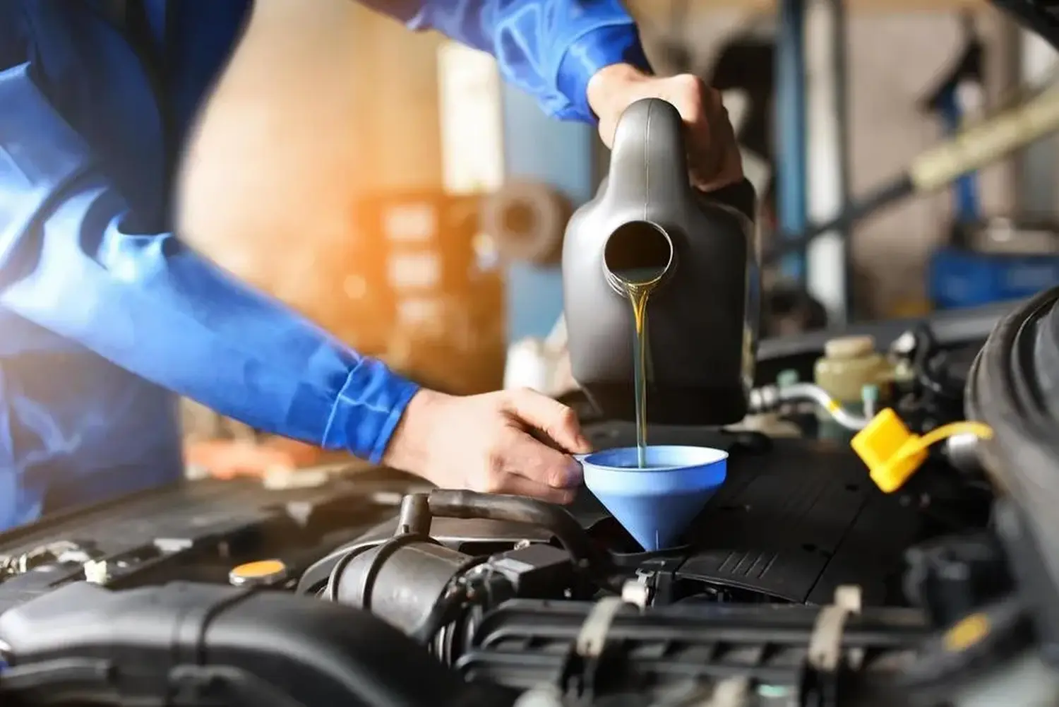 Mechaniker füllt Öl in der Werkstatt nach.